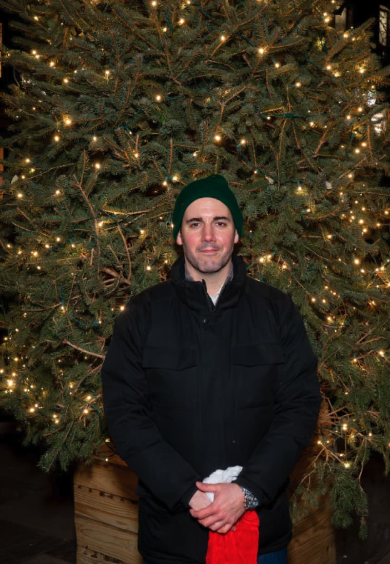 A visitor posing before the garden's lit Christmas tree